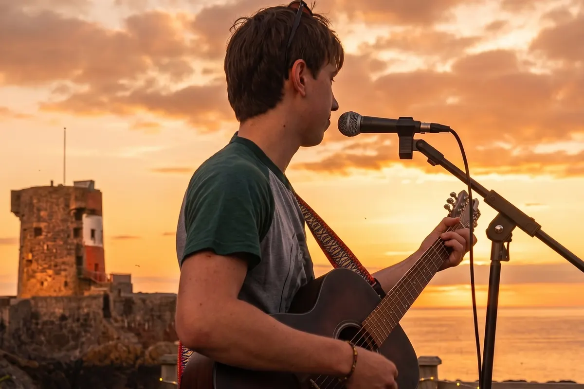 Live acoustic set at sunset, Archirondel Tower behind