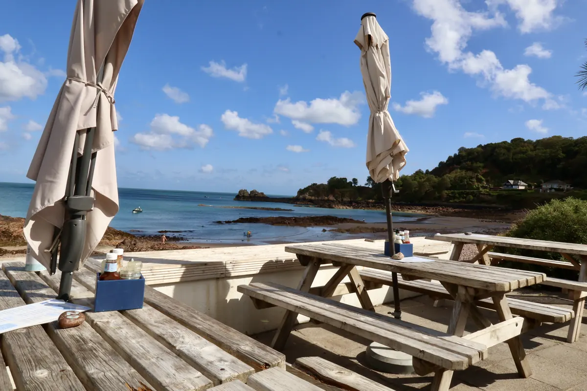 Umbrellas and picnic benches on the terrace above the bay
