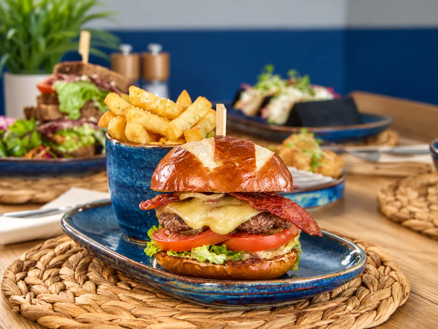 Bacon cheeseburger in a pretzel bun with a pot of chips